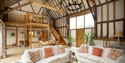 Spacious barn-style interior with exposed beams, mezzanine, wooden staircase and cosy seating area.