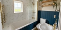 Modern bathroom at Beside The Sea Holidays with marble walls, blue panelling, gold fixtures, and shelving décor.