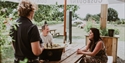 Outdoor wine tasting at Gusbourne Estate with visitors seated at a wooden table under branded parasols.