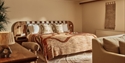 Stylish hotel room at Crafted at Powdermills with a large bed, earthy tones and textured décor.