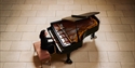 Pianist performing on a grand piano in a large stone‑tiled hall, viewed from above.