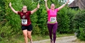 Image shows two runners in a running event for Nice Work. In the image, both parties have their hands raised