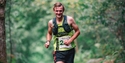 Image shows someone running in a nice work event. The background shows trees.