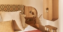 Image shows the inside of one of the bedrooms at Crafted at Powdermills, zoomed in on the corner of the bed and bedside table. The Room is bright, lig