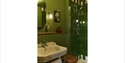 Image shows the inside of the bathroom at Crafted at Powdermills. The tiles are a dark green and the wall is painted a slightly lighter green. There i