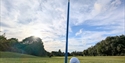 Image shows the golf course green with a focus on the golf ball near the hole.