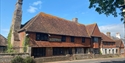 Historic Mint House in Pevensey with timber-framed upper floor and brick lower level, set against a clear sky.