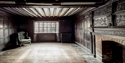 Interior room of the historic Mint House in Pevensey with wooden beams, fireplace, and rustic furniture.