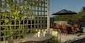 Garden at Stoats Holiday Home shows terrace and tables in sunshine