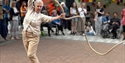 Outdoor performance by JUTE at De La Warr Pavilion, showing an older dancer swinging a rope as an audience watches.