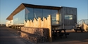 a photograph of Rye Harbour visitor centre. Wooden and glass structure against a blue sky.