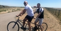 two men pose for the camera on their tandem bike.