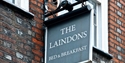 Sign for The Laindons boutique guesthouse mounted on a brick wall with greenery in the background.
