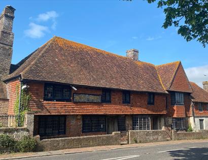Historic Mint House in Pevensey with timber-framed upper floor and brick lower level, set against a clear sky.
