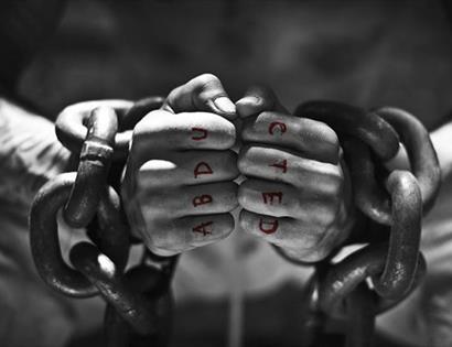 shackled wrists with fists clenched. Letters on knuckles read out ABDUCTED.