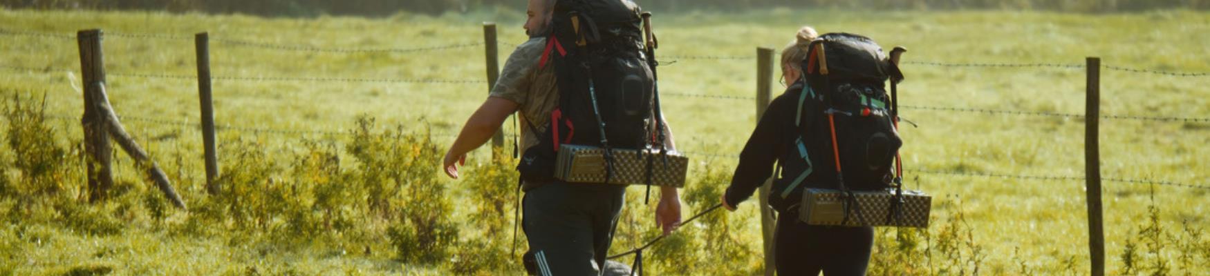 Walkers with backpacks following a countryside trail through rural 1066 Country.