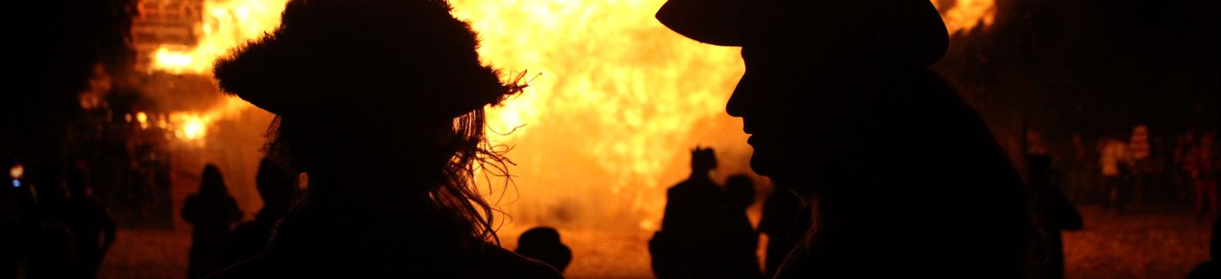 Silhouettes against the flames of a large bonfire