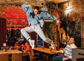 A man leaps into the air within a bar in Hastings.