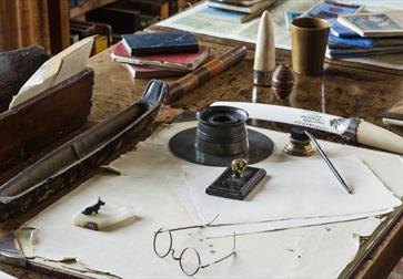 a writing desk with circular spectacles and items of stationery.