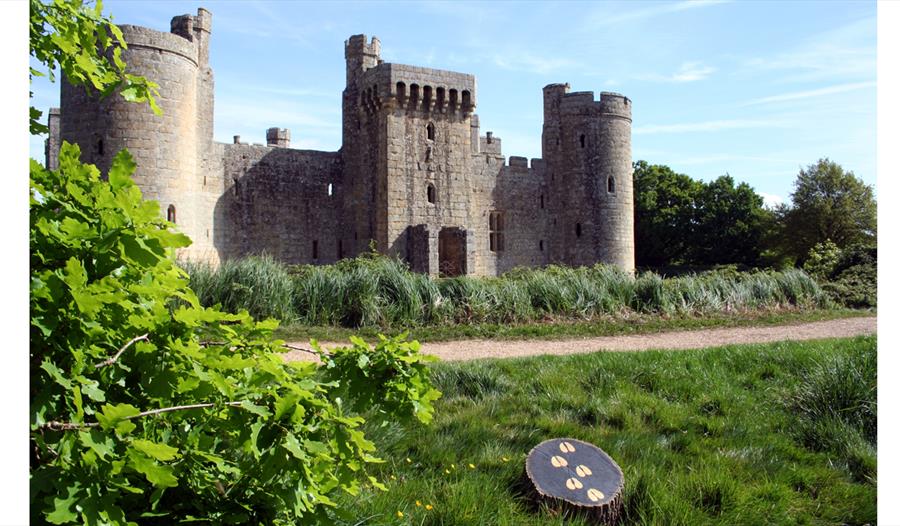photograph of turreted castle with grass lawn in foreground, includes a small plaque on grass with painted hoofprints