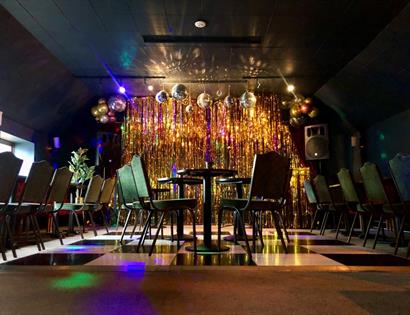 nightclub venue with glitterballs chequered floor and tables and chairs