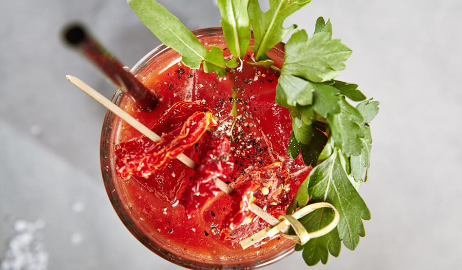 birds eye view of a bloody mary cocktail, red drink with celery leaves as gardnish
