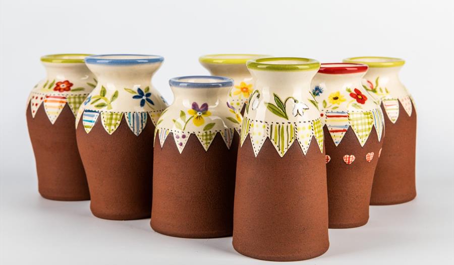 photo shows ceramic pots lined up with terracotta bases and glazed patterned tops.