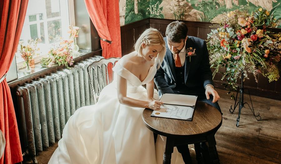 photograph of bride and groom signing a marriage register at The Bell in Ticehurst
