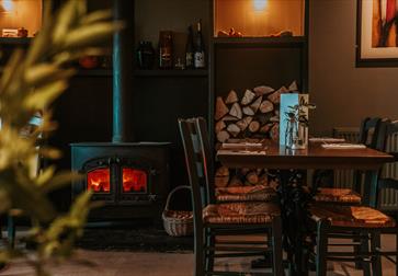 cosy pub interior with table and chairs next to a log burning stove.