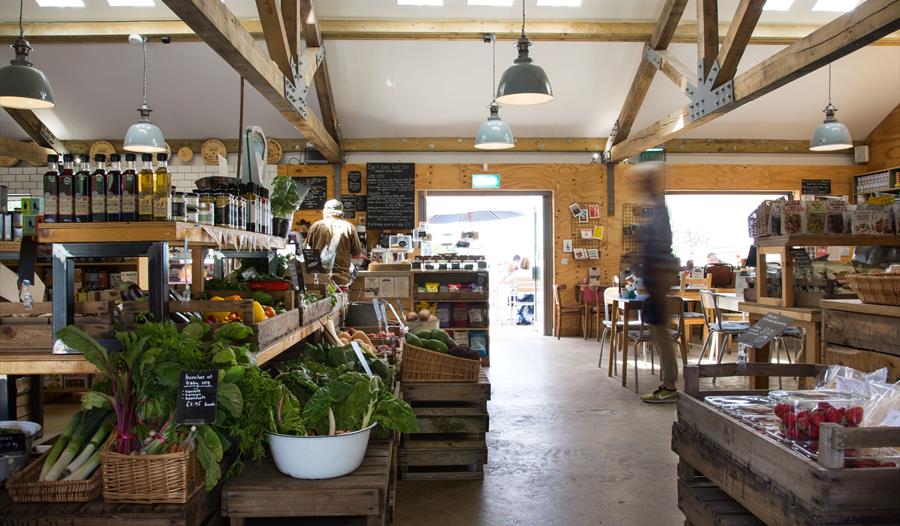 interior of farm shop with beams on ceiling and fresh salad leaves in foreground.