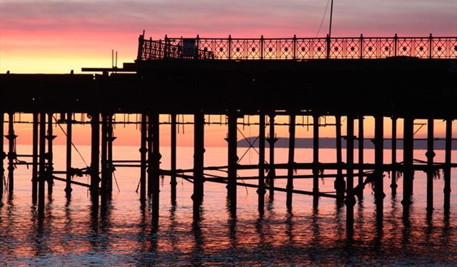 silhouetted pier structure against the sunset.