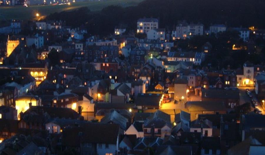 Twilight photograph of the town of Hastings. Looking down from the East Hill onto street lit houses.