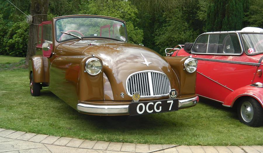 a vintage brown car parked on a lawn.