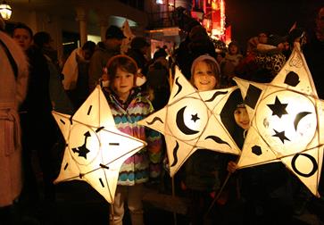 three children holding paper lanterns in the shape of stars