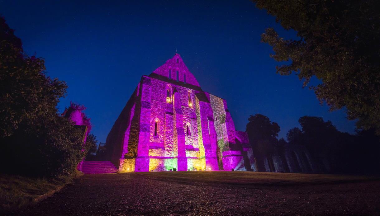 Battle Abbey illuminated at night in purple