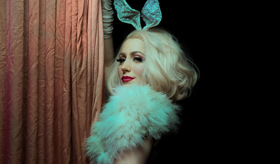 A photograph of a burlesque performer, with blonde hair and bunny ears. For an event at St Mary in the Castle Hastings