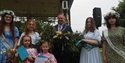 Group portrait of young women and girls with flowers and May queen sashes, stood with the Mayor.