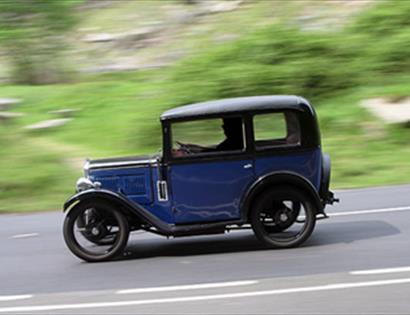 an Austin 7 vintage car on road with blurred background