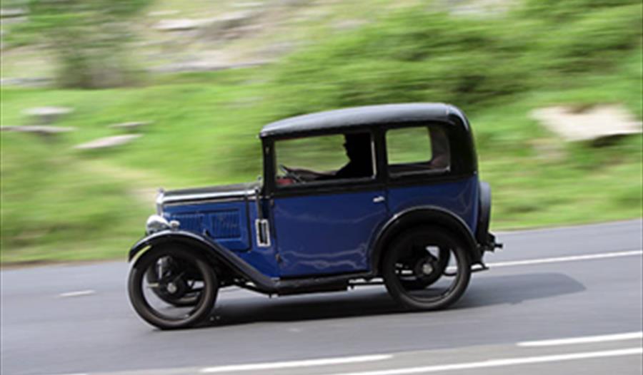 an Austin 7 vintage car on road with blurred background