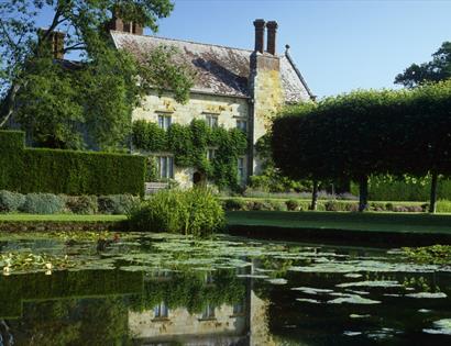 View of square pond and rural house a hedgerows
