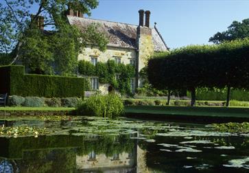 View of square pond and rural house a hedgerows