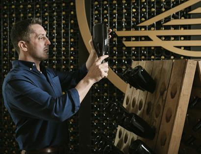 Man inspecting a bottle in a wine cellar.