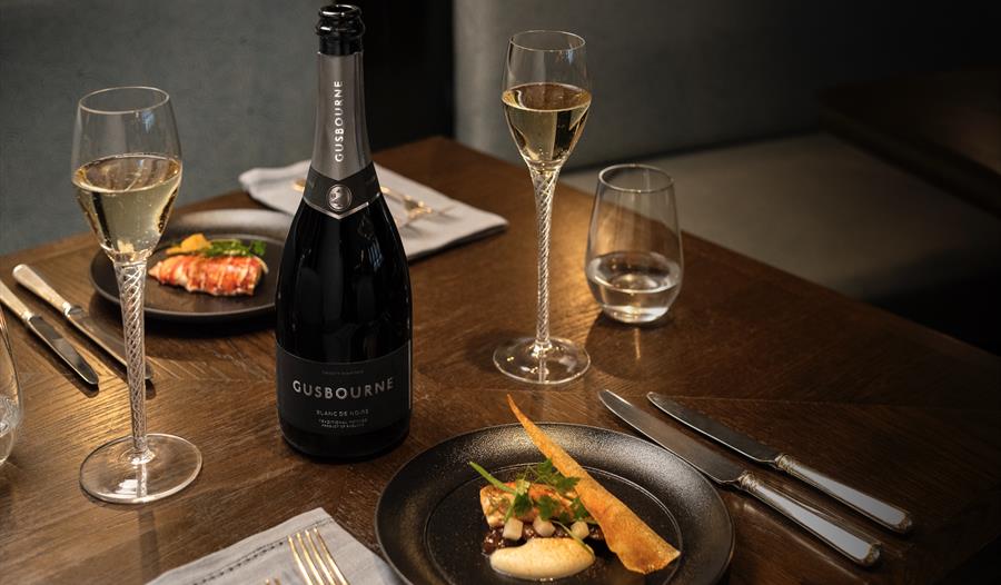 photograph of a dining table with food and bottle of Gusbourne sparkling wine