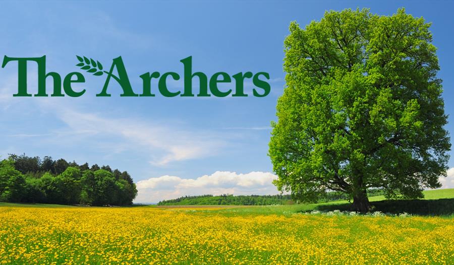 poster for the archers shows green text "The Archers" with yellow meadow and oak tree in the background.