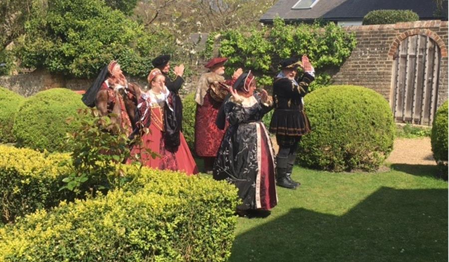 group dressed in tudor costume on grass lawn of michelham priory.