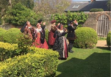 group dressed in tudor costume on grass lawn of michelham priory.
