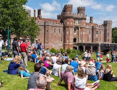 large group sat on lawn before herstmonceux castle