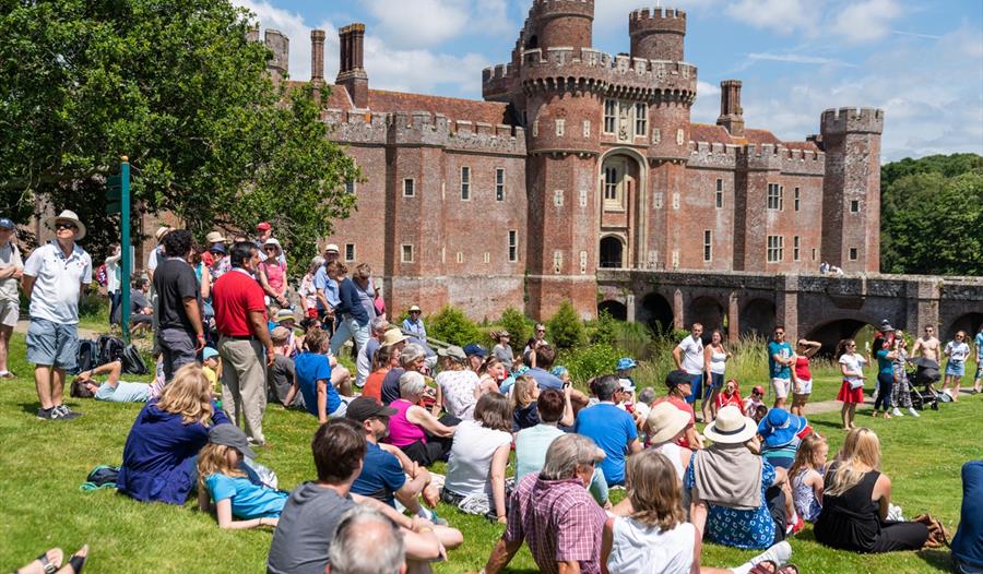 large group sat on lawn before herstmonceux castle