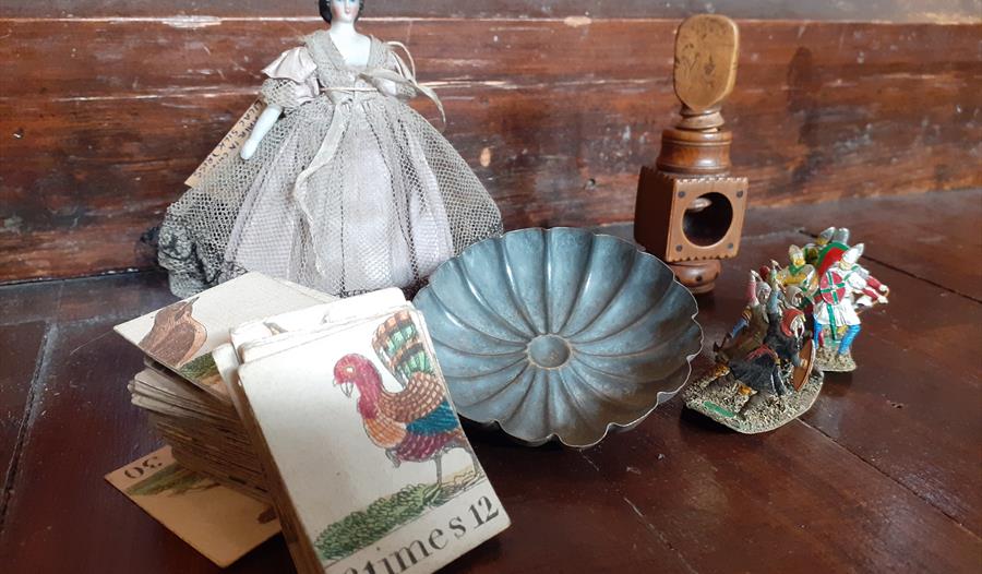 photograph of vintage toys placed together, including a porcelain doll and cards.
