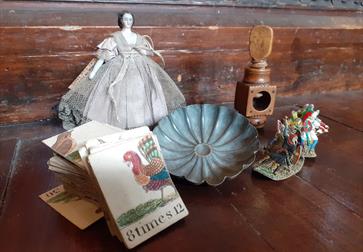photograph of vintage toys placed together, including a porcelain doll and cards.